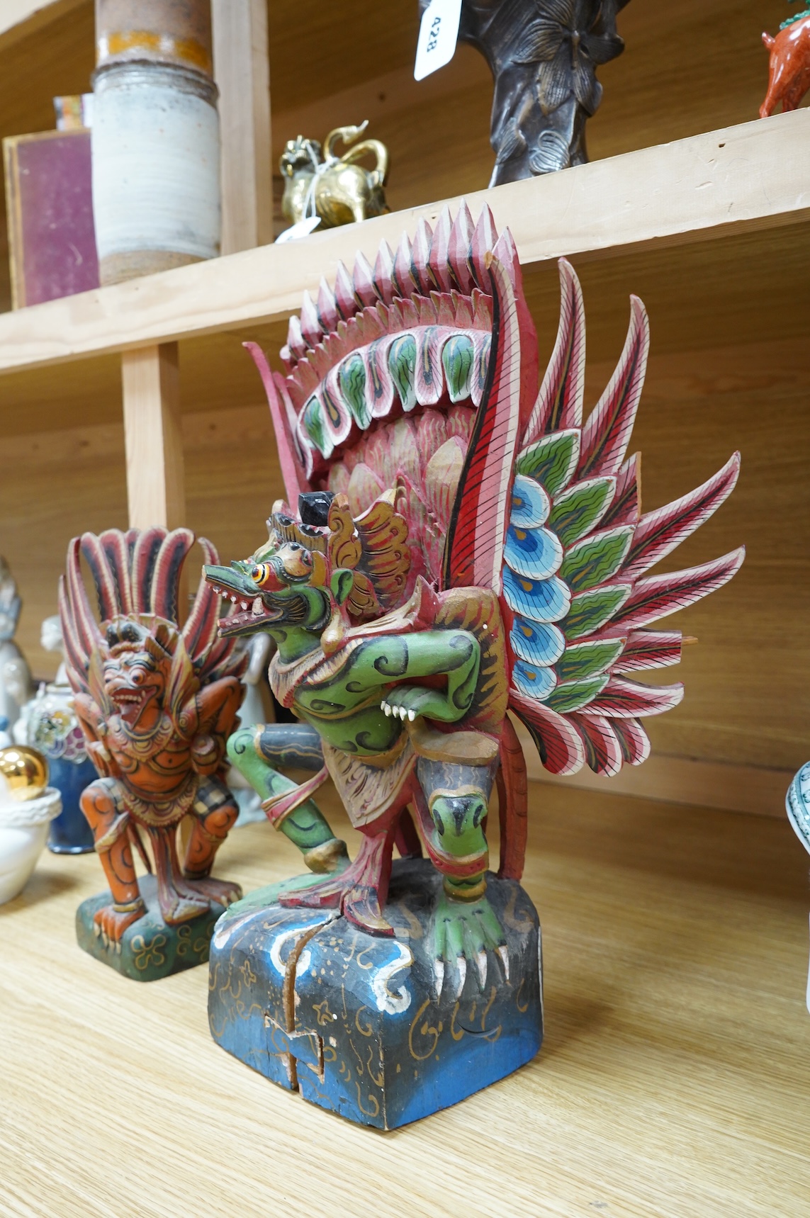 A Balinese painted and carved wood sculpture of Garuda, together with a smaller similar carving, largest 46cm high